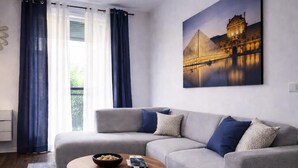 A modern living room with a grey sofa, a round coffee table, and a blue rug. - Magic Stay Val d' Europe (Chessy)
