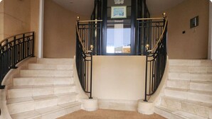 A grand staircase with marble steps and black iron railings, leading to an upper floor. - Magic Stay Val d' Europe (Chessy)