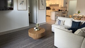 Un salon moderne avec un canapé, une table basse et une cuisine en arrière-plan.