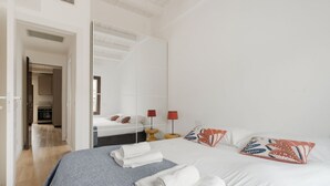 Et hotelværelse med en seng, et spejl, et sengebord med en lampe og udsigt til et køkken.