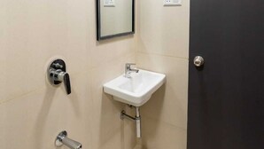 Un baño pequeño y moderno, con un lavamanos blanco, un espejo y una ducha.