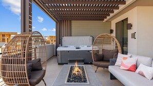 Une terrasse sur le toit dotée d’un foyer extérieur, de sièges et d’un jacuzzi.