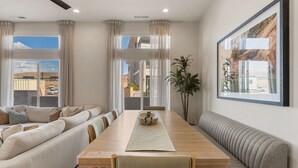 Un salon moderne avec un canapé, une table à manger et une grande fenêtre agrémentée de rideaux.