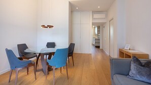 A modern living room with a glass dining table, blue and gray chairs, a gray sofa, and a wooden floor. - easyhomes - Piazza Erculea (Milan)