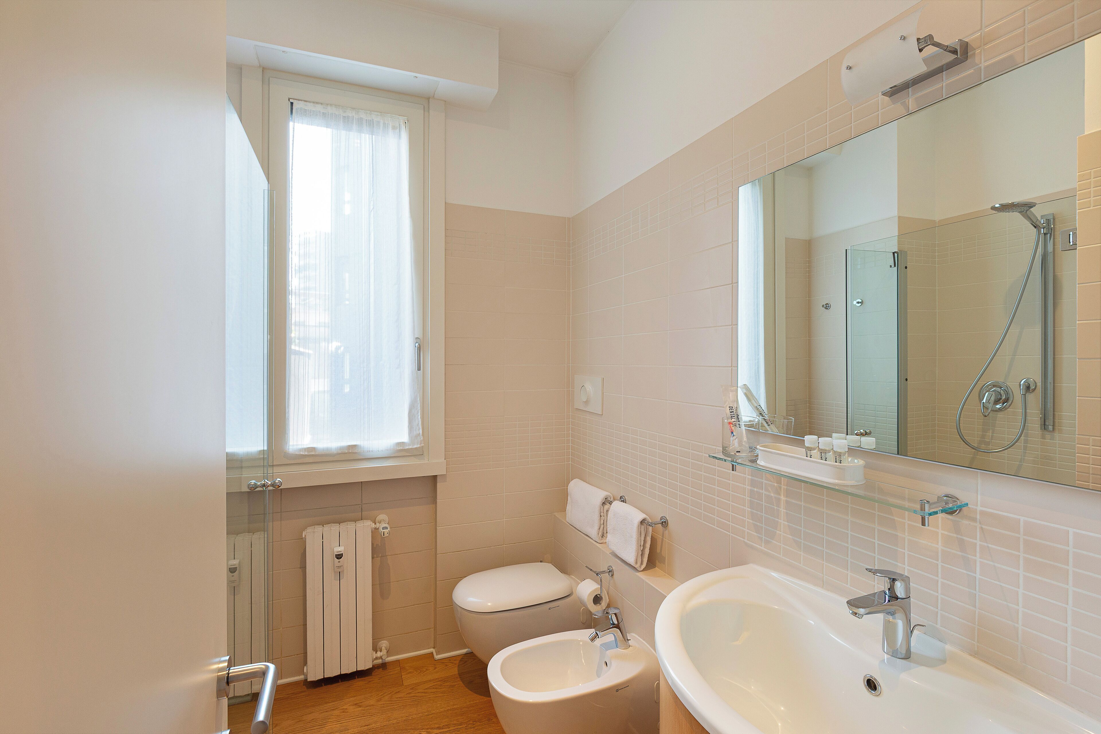 Un baño con inodoro, bidé, lavamanos y cabina de ducha de cristal.