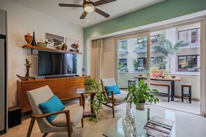 Ein modernes Wohnzimmer mit Flachbildfernseher, Holzmöbeln und einem Balkon mit Pflanzen.
