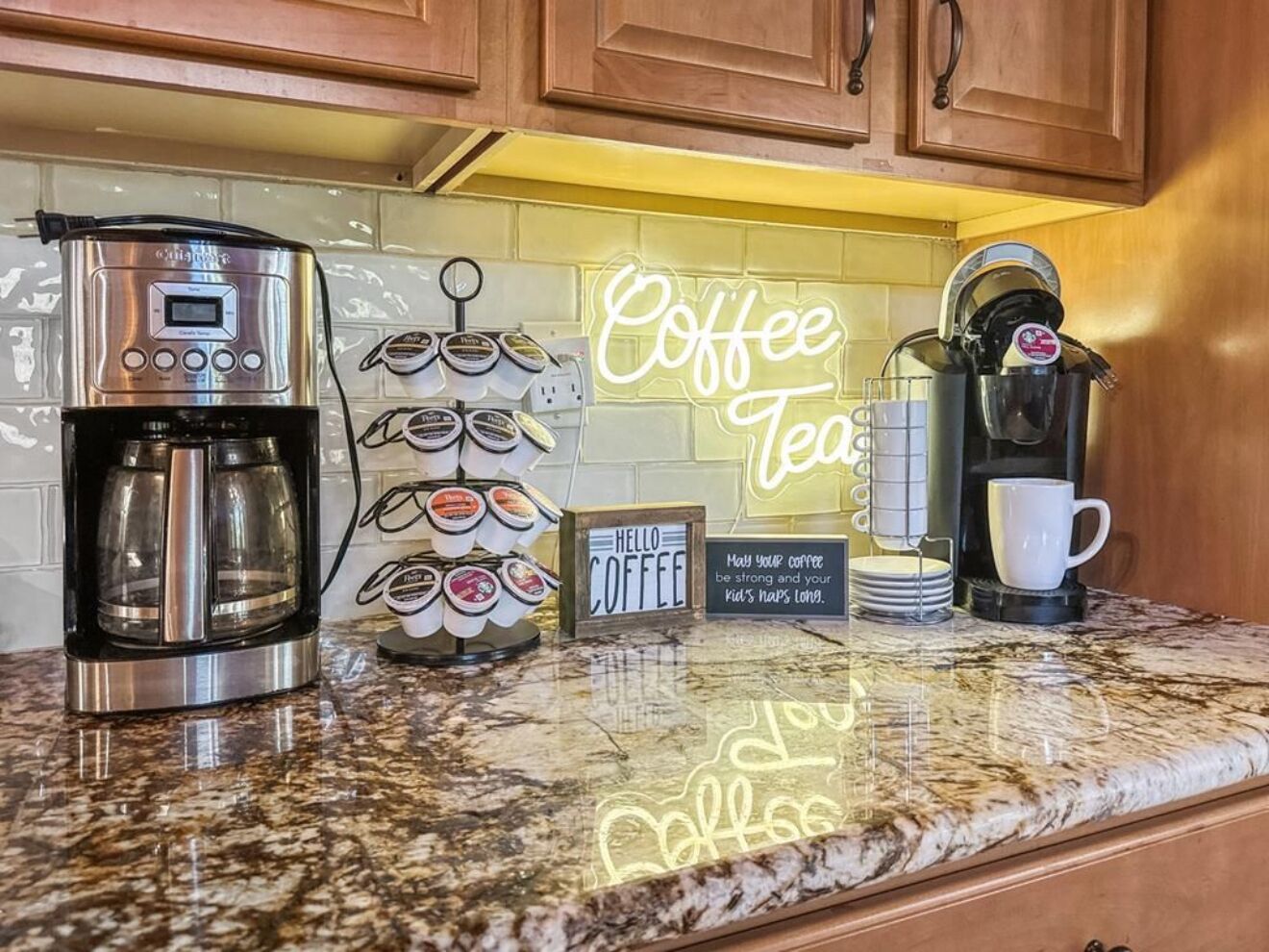 A kitchen with a coffee maker, a coffee cup, and a coffee mug on the counter.