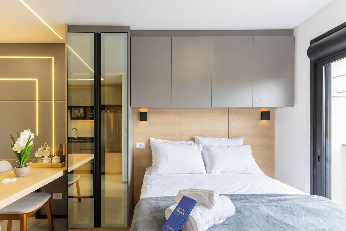 Una habitación de hotel moderna con una cama, mesita de noche y un espacio de escritorio con sillas.
