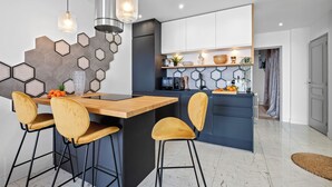 Una cocina moderna con una isla de madera, taburetes de bar y un refrigerador empotrado.