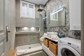 A modern bathroom with a glass-enclosed shower, a built-in sink, and a washing machine. - Baie des Anges (Nice)