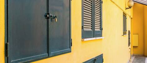 A corridor with yellow walls, black shutters, and a tiled floor.