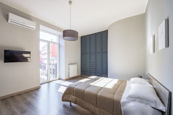 Une chambre moderne avec un grand lit, une armoire intégrée et un téléviseur fixé au mur.