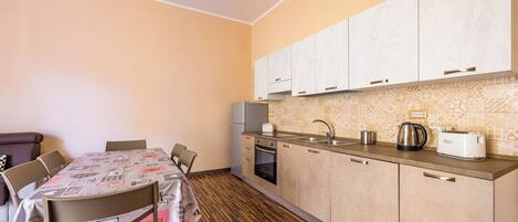 Una cocina compacta con zona de comedor, que presenta piso de madera, horno integrado y pileta con hervidor y tostadora.