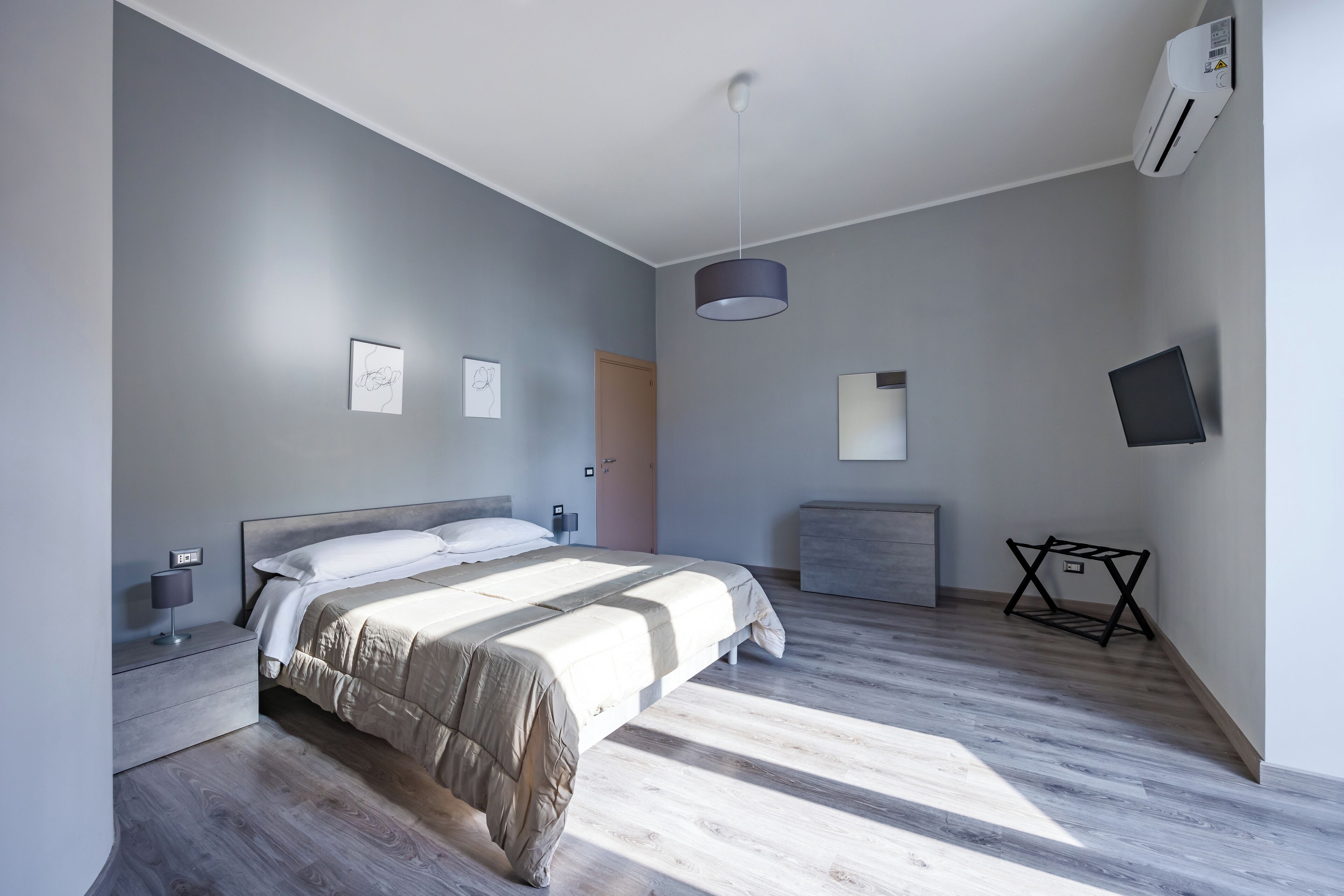 Une chambre moderne équipée d’un lit, d’une table de chevet, d’une lampe, d’un climatiseur et d’un téléviseur.