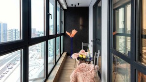 A modern balcony with large windows, a wooden floor, and a table with chairs. - Apartments near Aerodromnaya metro st (Minsk)