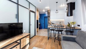 A modern living room with a TV, sofa, and kitchen area with bar stools. - Apartments near Aerodromnaya metro st (Minsk)