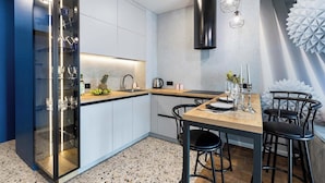 A modern kitchen with a built-in wine rack, a dining area with a wooden table and black chairs, and a unique wall decoration. - Apartments near Aerodromnaya metro st (Minsk)