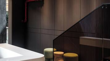 A modern interior with a white sink, wooden panel walls, red pipes, and a glass staircase.