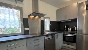 Eine moderne Küche mit Edelstahlgeräten, grauen Schränken und einem Fenster mit Blick auf Grünflächen.