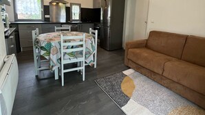 Ein kompakter Wohnbereich mit Küchenzeile, einem Essbereich mit Tisch und Stühlen sowie einer Couch.