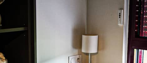 Ein Schreibtisch mit Lampe, ein Stuhl und ein Fenster mit Jalousien.