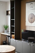 Uma cozinha moderna com televisão integrada, uma planta e uma estante de livros.