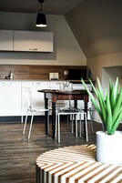 Uma cozinha moderna com armários brancos, uma mesa de jantar de madeira e um vaso com planta.