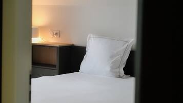 Un dormitori amb un llit, una tauleta de nit, una làmpada i una làmpada penjant.