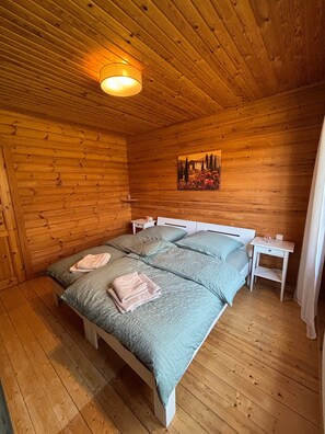 Puupaneelilla verhoiltu huone, jossa on sänky, yöpöytä, seinällä oleva taulu ja kattovalaisin.