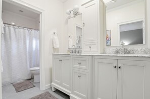 A bathroom with a shower, toilet, and vanity with a mirror and sink. - 0.2 Mi to Beach • 3 Ensuite Baths • Sleeps 10 • Walk to King & Prince (St Simons)