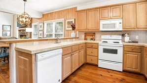 A modern kitchen with wooden cabinets, a built-in dishwasher, a microwave, and a stove. - 0.2 Mi to Beach • 3 Ensuite Baths • Sleeps 10 • Walk to King & Prince (St Simons)