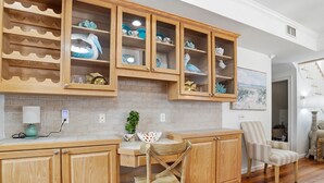 A kitchen with wooden cabinets, a dining table, and chairs. - 0.2 Mi to Beach • 3 Ensuite Baths • Sleeps 10 • Walk to King & Prince (St Simons)