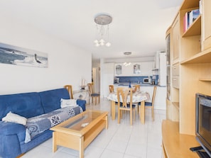A living room with a blue sofa, a glass coffee table, and a TV stand. - Apartment for 4 with balcony – City center (Sarzeau)