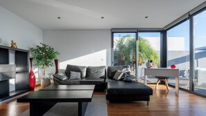 A modern living room with a sofa, coffee table, and a desk with a chair. - Oceanfront Villa with Private Pool - Breathtaking Sunsets in Madeira (Tabua)