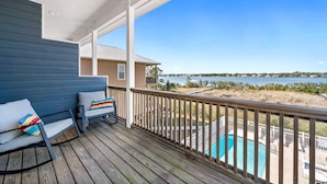 A wooden deck with a pool, a chair, and a view of a body of water. - Lagoon-front Duplex w/Fishing Pier Sleeps 24/BM (Gulf Shores)