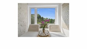 A room with a large window, a round table with a plant, and two chairs. - Riverfront Estate in Paris, 5 luxury Suites indoor pool hot tub self serve spa (Brant)