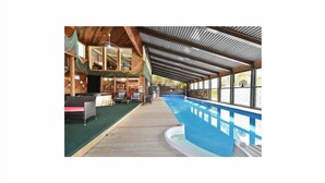 A pool area with a wooden deck, lounge chairs, and a covered seating area with a view of the pool. - Riverfront Estate in Paris, 5 luxury Suites indoor pool hot tub self serve spa (Brant)