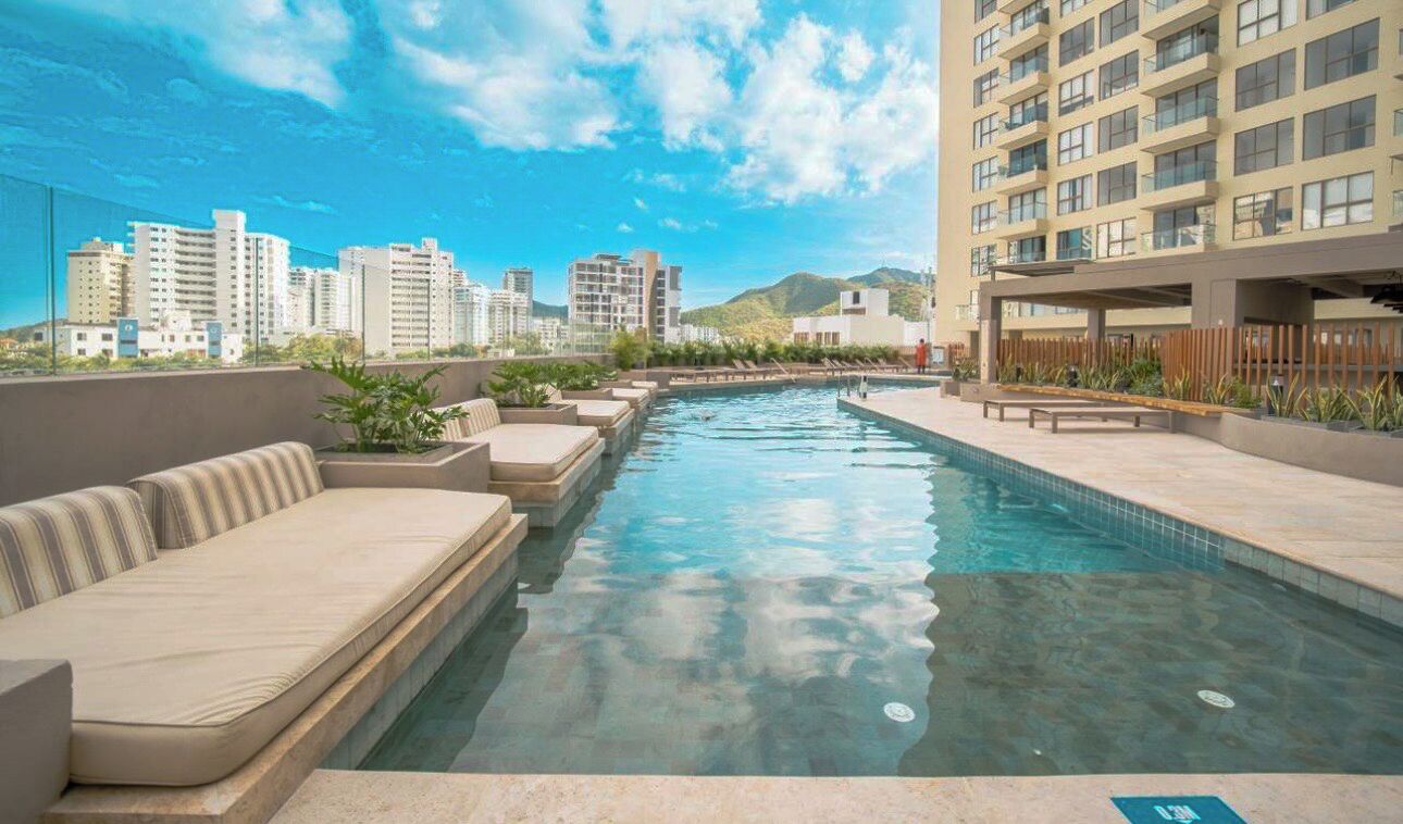 Une piscine sur le toit, agrémentée de chaises longues, offrant une vue dégagée sur le paysage urbain et mettant en valeur les bâtiments modernes en arrière-plan.