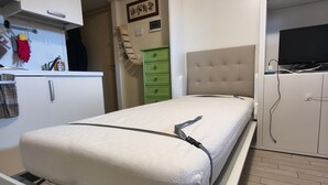 A compact bedroom with a bed, a small kitchenette, a green dresser, and a television. - Modern & Practical Studio in Sauze d'Oulx (Sauze d'Oulx)