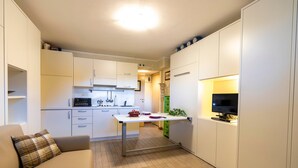 A compact living space with a kitchenette, a dining table, a sofa, and a television. - Modern & Practical Studio in Sauze d'Oulx (Sauze d'Oulx)