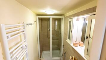 A bathroom with a glass-enclosed shower, a toilet, and a sink.