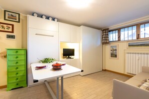 Une cuisine moderne avec des meubles blancs, une table à manger, un meuble vert et une fenêtre avec des rideaux.