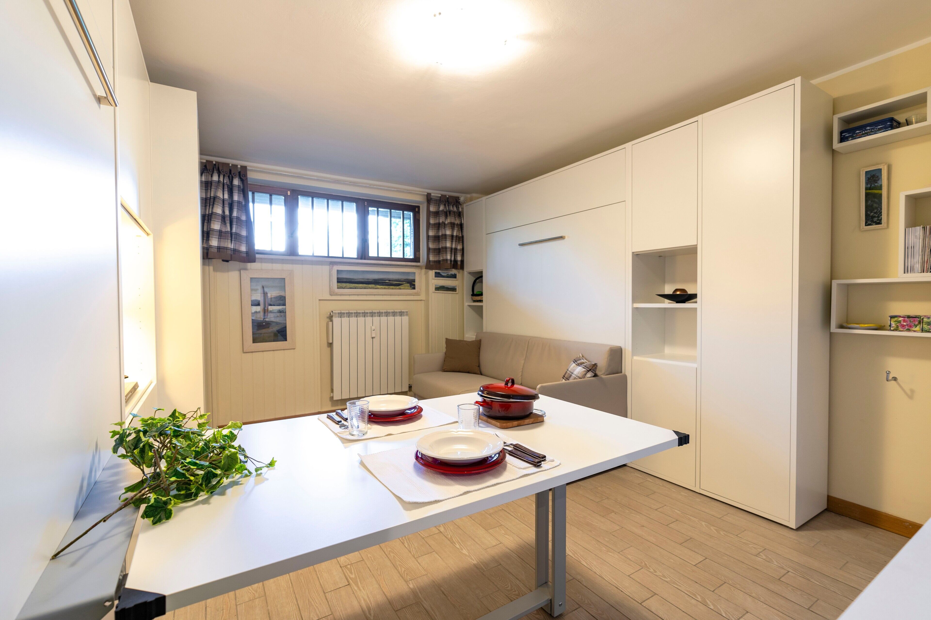 Una cucina compatta con un tavolo da pranzo per due persone, un termosifone e una finestra con tende.