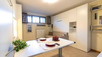 Una cucina compatta con un tavolo da pranzo per due persone, un termosifone e una finestra con tende.