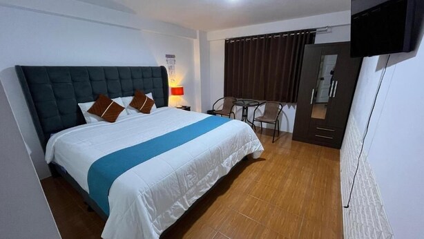 Een hotelkamer met een bed, bureau en televisie.