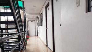 Een gang met een metalen leuning aan de linkerkant, deuren met de nummers 301 en 302, en een betegelde vloer.