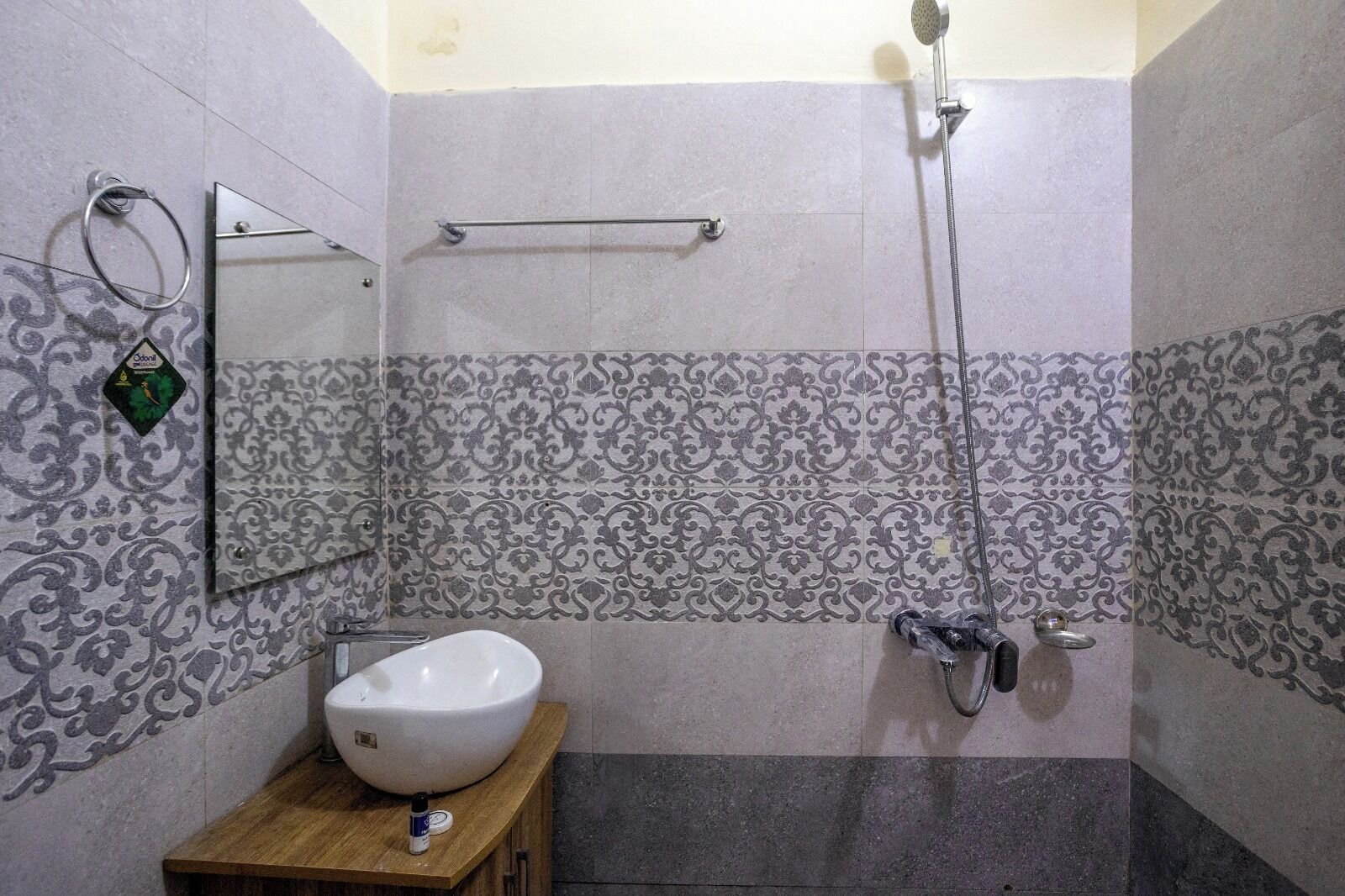 A bathroom with a large sink, a handheld showerhead, and a towel rack.