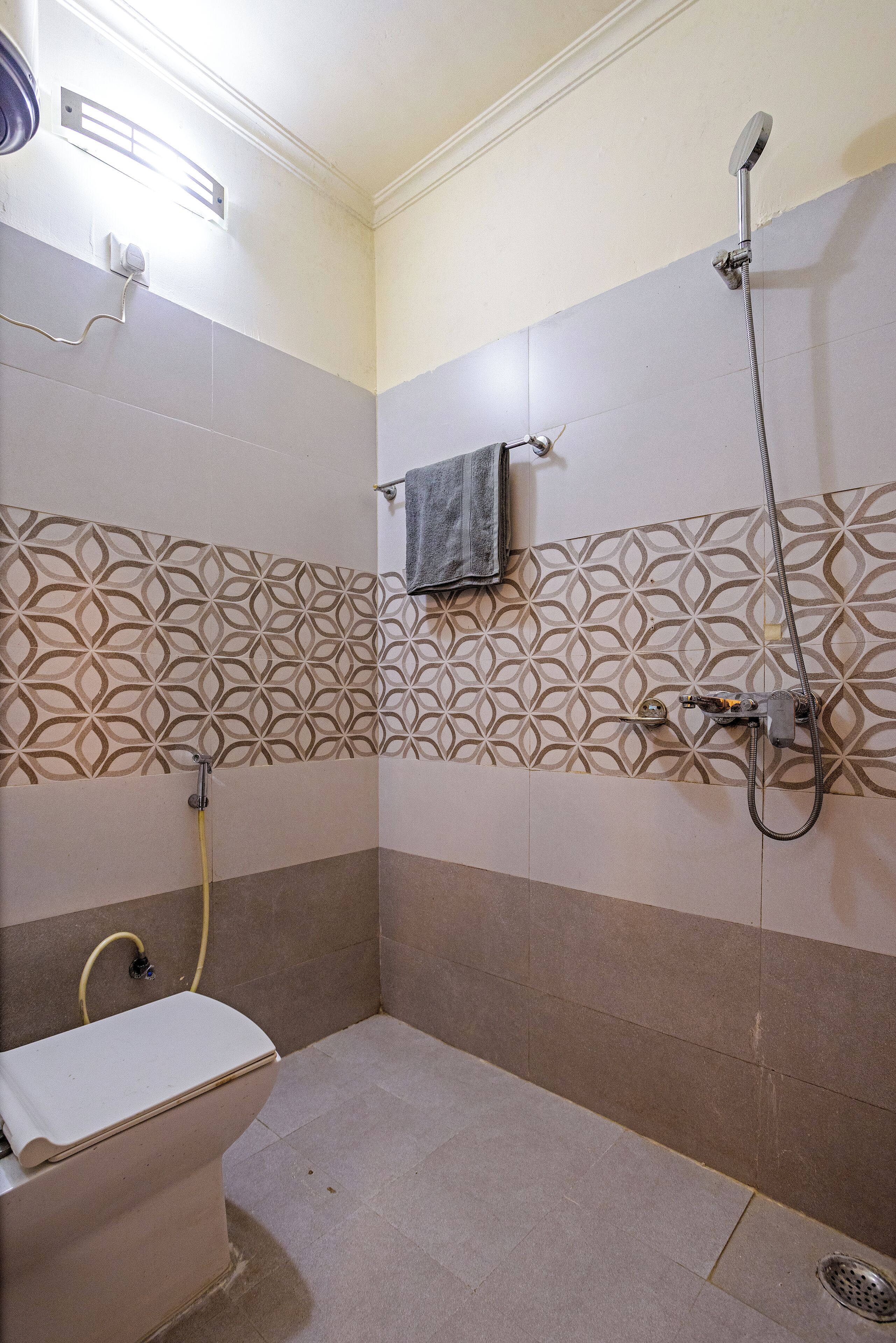 Ein Badezimmer mit Toilette, Dusche und Wandfliesen mit Muster.