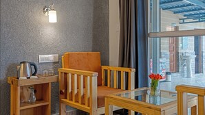 A cozy seating area with a wooden chair and table, a kettle, and a vase with flowers. - Dimmys By the Lake Bhimtal (Bhimtal)