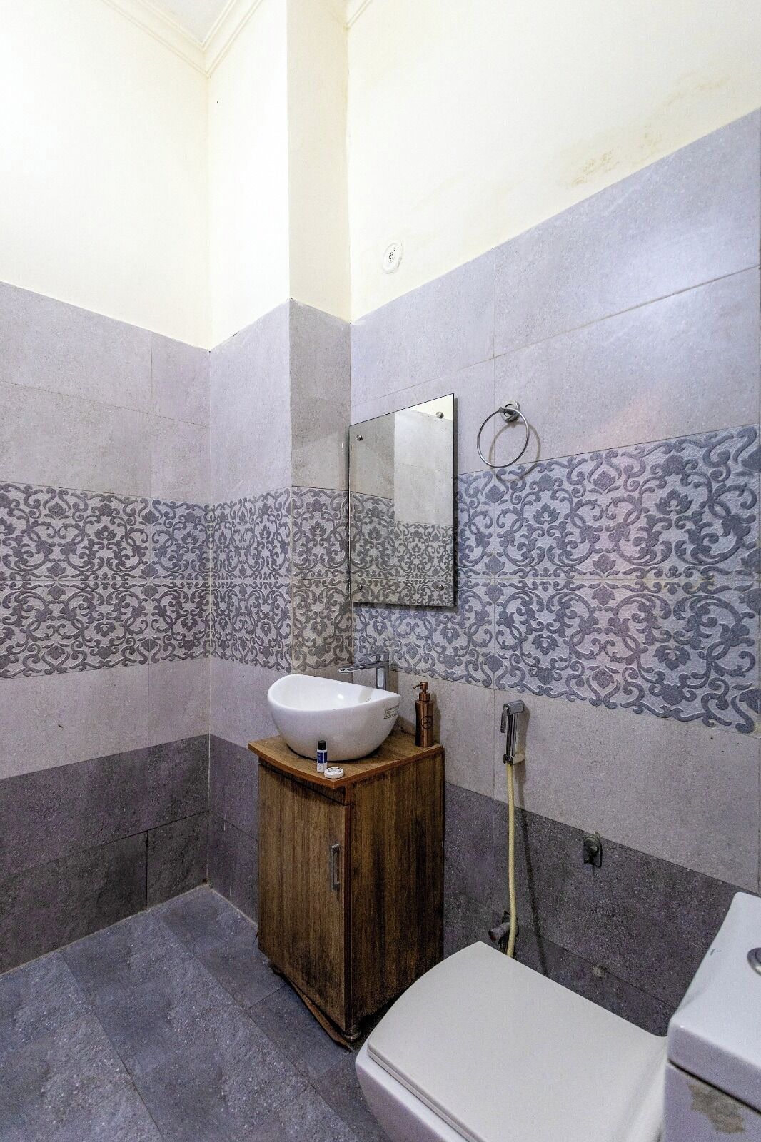 A bathroom with a white sink, wooden cabinet, and a mirror on the wall.